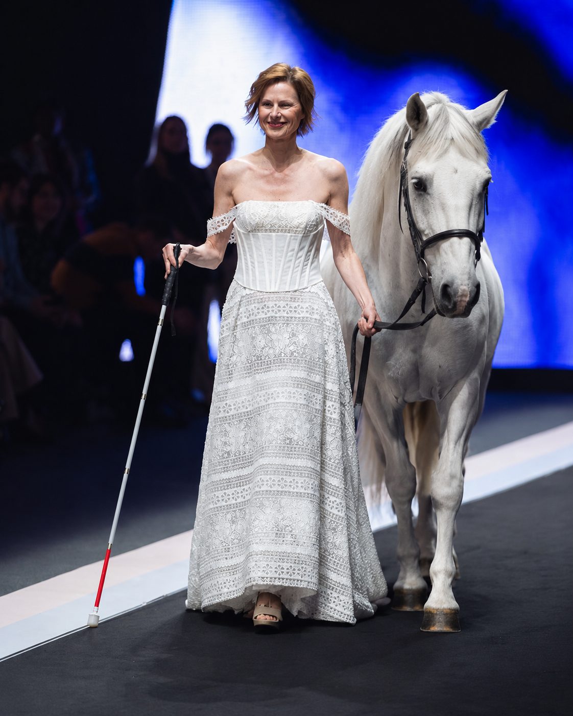 Modella in abito da sposa in pizzo con cavallo bianco in passerella